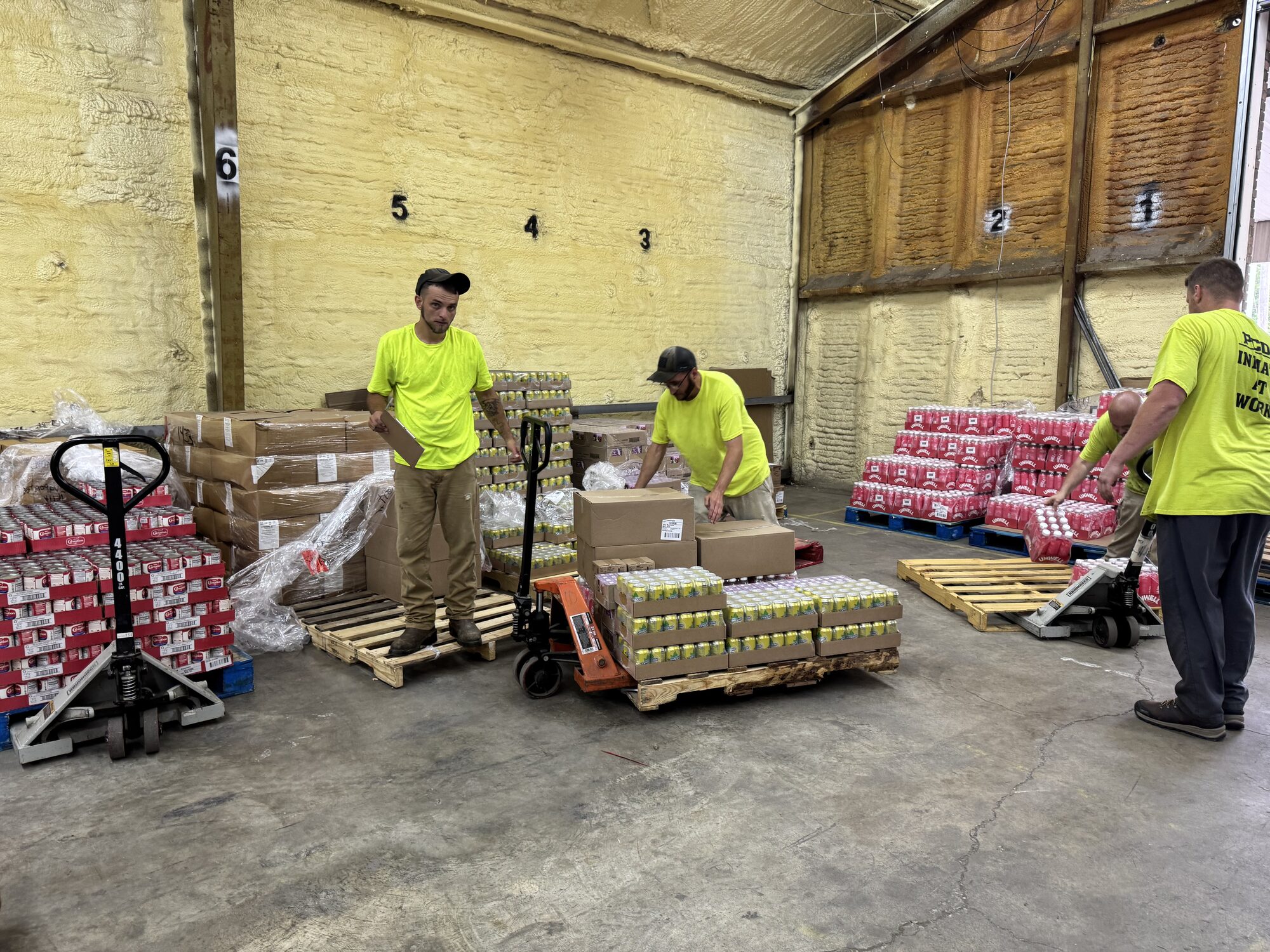 Volunteers assemble pallets of food inside the Servants of our Lord Ministry warehouse in preparation for the monthly food distribution.